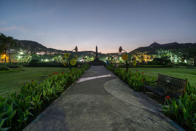 Footpath in garden against sky during sunset