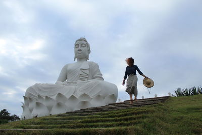 Unidentified tourist  walking beside a statue of buddha in ibiraçu, espírito santo, brazil