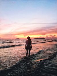 Rear view of silhouette man standing on beach during sunset