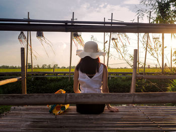 Rear view of woman on railing against sky