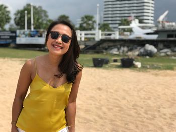 Portrait of smiling woman wearing sunglasses standing at beach