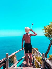 Man standing by railing against sea