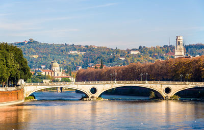 Bridge over river by buildings against sky