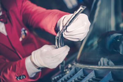 Midsection of manual worker repairing windshield wiper