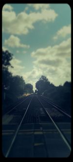 Railroad track against cloudy sky