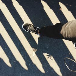 Low section of person with shadow on road