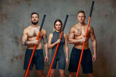 Portrait of athletes with katana against wall