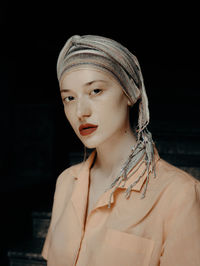 Portrait of young woman against black background