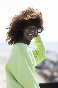 Smiling woman with tousled hair standing outdoors