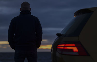 Adult man standing against car looking at view during sunset. almeria, spain