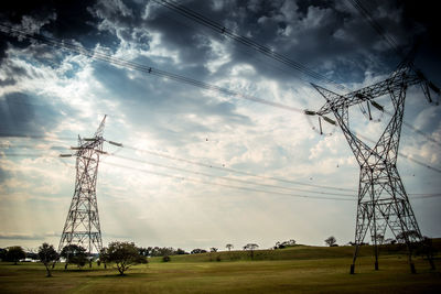 Low angle view of electricity pylon on field against sky