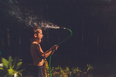 Side view of shirtless woman standing on field at night