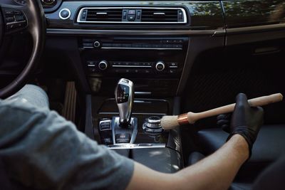 Cropped image of man cleaning button in car