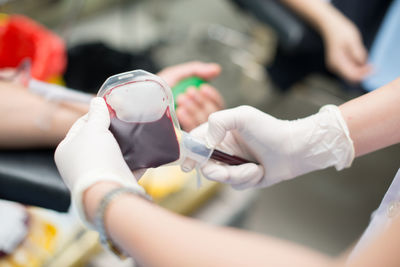 Cropped hands of doctor holding blood bag in hospital