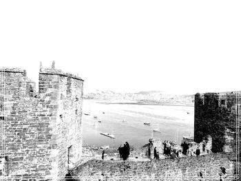 People on the wall of fort against clear sky