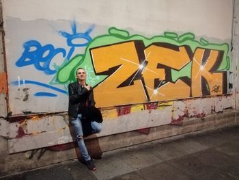 Full length of woman standing against graffiti wall