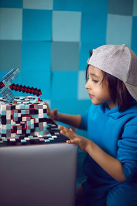 Boy in blue clothes looks at a cake pixels with a pickaxe in the studio. birthday five years