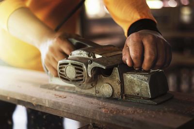 Cropped hands of carpenter holding work tool