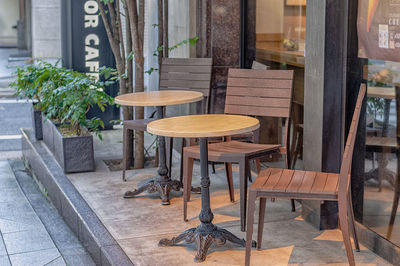 Empty chairs and tables at sidewalk cafe