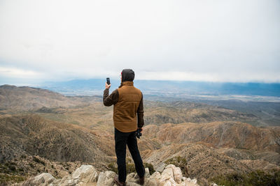 Rear view of man photographing on mountain