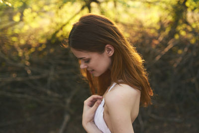 Young woman looking away while standing on land