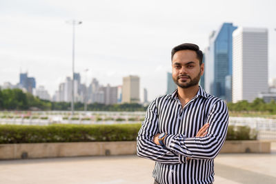 Portrait of young man standing against buildings in city