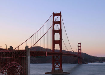 Golden gate bridge over river against sky during sunset