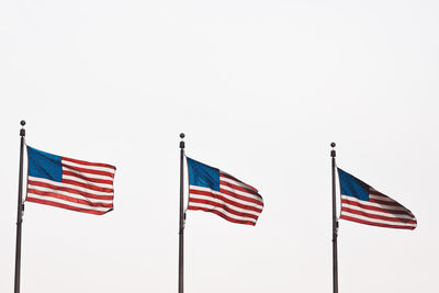 Low angle view of american flags fluttering against clear sky
