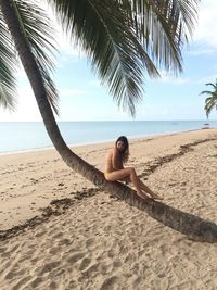 Woman sitting on tree trunk at beach