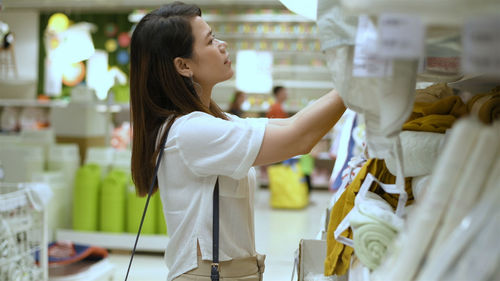 Side view of a young woman standing in store