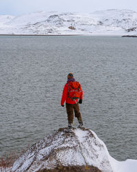 Rear view of man standing on rock by sea