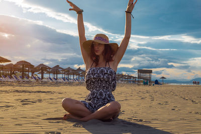 Full length of woman sitting on beach against sky