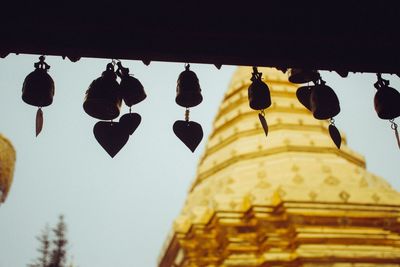 Low angle view of lanterns hanging by building against sky