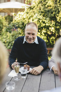 Portrait of happy senior man having dessert with friends at cafe table