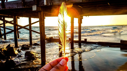 Close-up of hand holding sea against sky