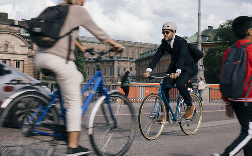 Full length of businessman riding bicycle on street in city