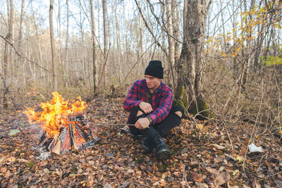 Man roasting food in campfire at forest