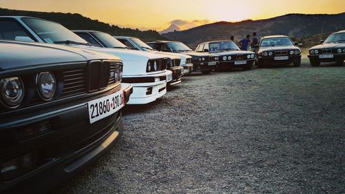 Vehicles on road against sky at sunset