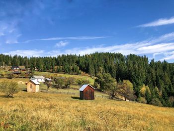 Scenic view of trees and houses on field against sky