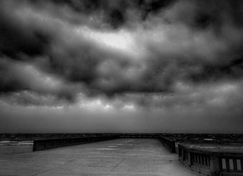 Pier on sea against cloudy sky