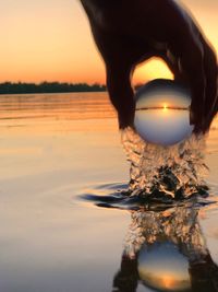 Reflection of person in lake against sky during sunset