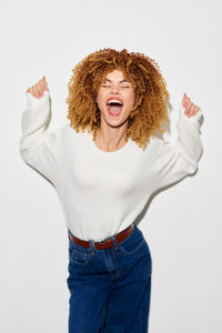 Portrait of young woman standing against white background