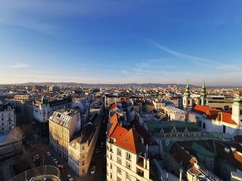 High angle view of city buildings against blue sky