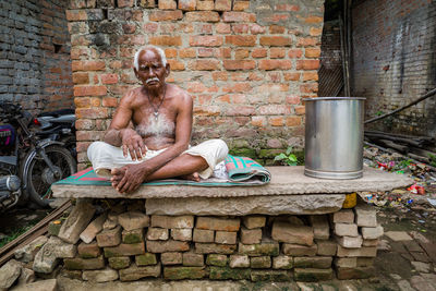 Portrait of man sitting on brick wall