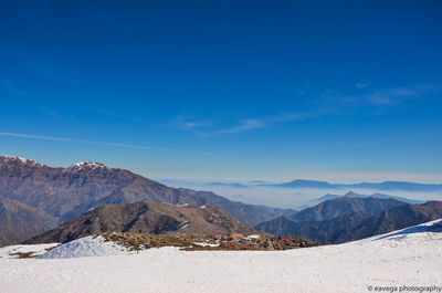 Scenic view of snowcapped mountains against blue sky