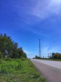 Road by trees against blue sky