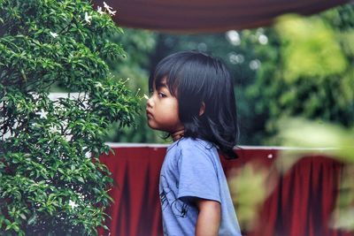 Girl looking away while standing against plants
