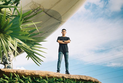 Low angle portrait of young man standing against sky