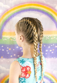 Side view of girl with braided hair standing against wall