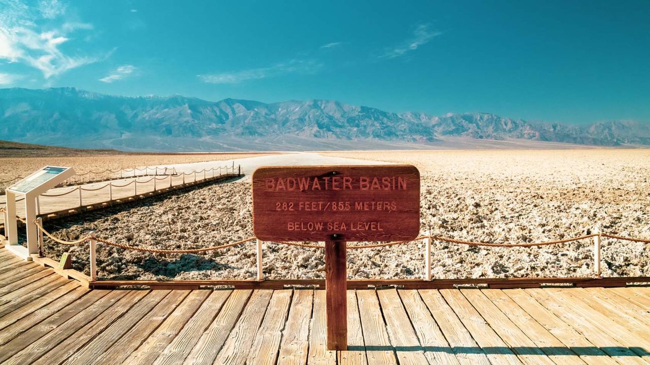 text, communication, western script, wood - material, sign, mountain, sky, day, no people, scenics - nature, nature, land, beauty in nature, landscape, information, tranquil scene, tranquility, blue, travel destinations, capital letter, outdoors, climate